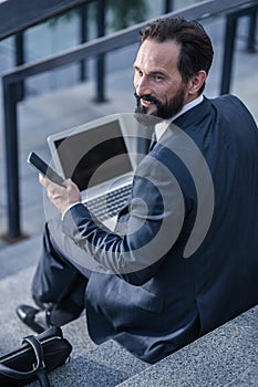 Smiling handsome businessman sitting on the staircases outdoors