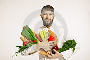 Smiling handsome chef with vegetables in hands on white