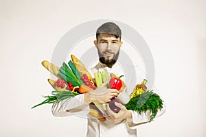 Smiling handsome chef with vegetables in hands on white