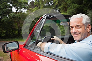 Smiling handsome man driving red cabriolet