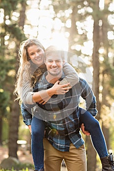 Smiling handsome man giving piggy back to his girlfriend