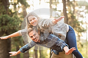 Smiling handsome man giving piggy back to his girlfriend