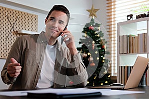 Smiling handsome man sitting in living room and talking on mobile phone