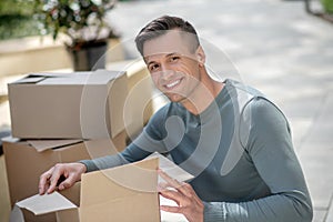 Smiling handsome man sitting next to the cardboards