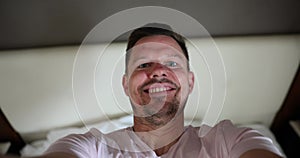 Smiling handsome man takes selfie and falls on hotel bed