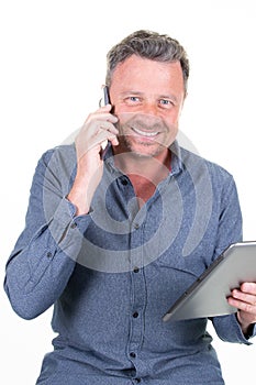 Smiling handsome man talking on a mobile phone while looking tablet computer screen  isolated on white background