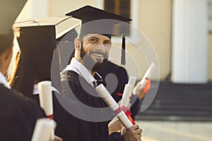 Smiling handsome man university graduate holding diploma with honors