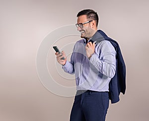 Smiling handsome manager with blazer using smartphone for social media marketing on white background