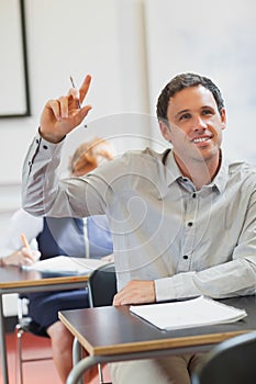 Smiling handsome mature student raising his hand