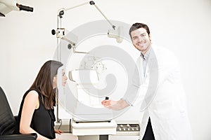 Smiling handsome optician checking young woman eyes