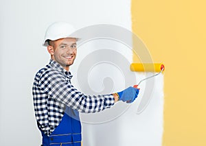 Smiling handsome painter painting the wall in beige