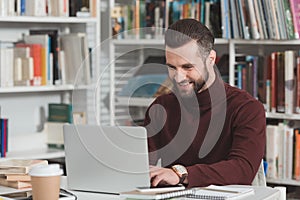 smiling handsome student using laptop