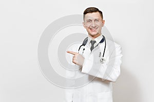 Smiling handsome young doctor man isolated on white background. Male doctor in medical gown, stethoscope pointing index