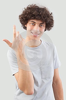 Smiling and handsome a young man with curly hair he looks into the camera with his blue eyes, gesturing with his hands, a portrait