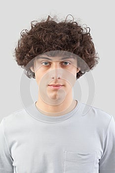 smiling and handsome a young man with curly hair he looks into the camera with his blue eyes, portrait of guy isolated against a