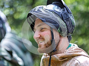 Smiling handsome young man in opened paintball mask