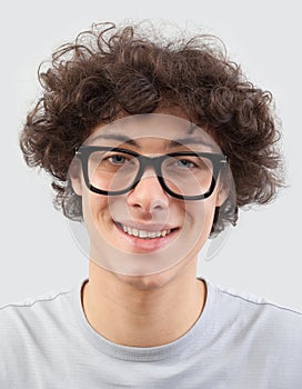 Smiling and handsome, the young man wears glasses. He looks into the camera with his blue eyes, man portrait with eyeglasses