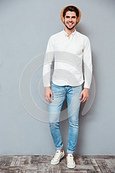 Smiling handsome young man in white shirt, jeans and hat