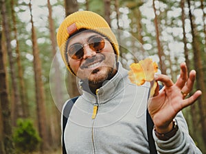 Smiling handsome young person finds mushroom in a deep pine forest in autumn