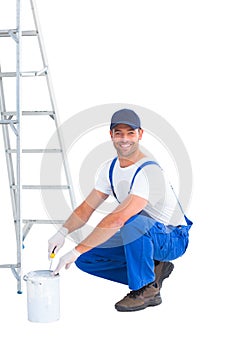 Smiling handyman in overalls opening paint can