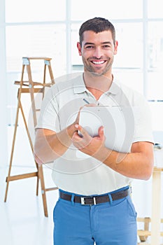 Smiling handyman writing on clipboard at construction site