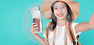 Smiling happily Asian woman traveler holding passport with ticket and map, money on blue background.