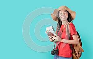 Smiling happily Asian woman traveler holding passport with ticket and map, money on blue background.