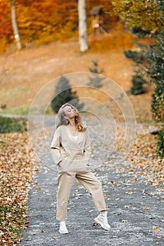 Smiling happy active woman on the path in autumn near the forest