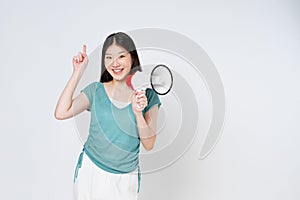 Smiling happy asian girl holding megaphone and pointing up, announcing discount promo, showing advertisement on top, standing over