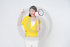 Smiling happy asian girl holding megaphone and pointing up, announcing discount promo, showing advertisement on top, standing over