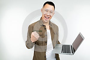 Smiling happy asian man holding a laptop in his hands on a white studio background