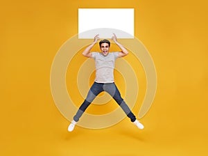 Smiling happy Asian man jumping and holding blank speech bubbles on yellow background. advertise announcement concept
