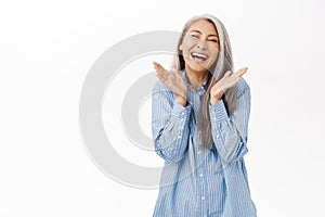 Smiling happy asian senior woman. Old japanese female with gray hair laughing and looking upbeat, standing over white