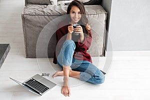 Smiling happy asian woman drinking cup of coffee