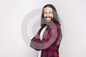 Smiling happy bearded man standing with crossed arms, expressing confidence.