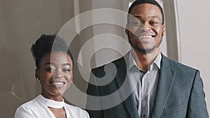 Smiling happy beautiful African American businessman and businesswoman professional managers workers looking at camera