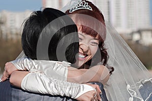 Smiling happy bride embracing groom