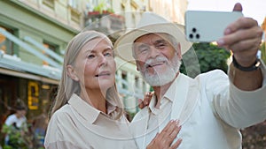 Smiling happy Caucasian old senior retired family couple travelers tourists taking selfie photo on mobile phone camera