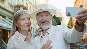 Smiling happy Caucasian old senior retired family couple travelers tourists taking selfie photo on mobile phone camera