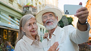 Smiling happy Caucasian old senior retired family couple travelers tourists taking selfie photo on mobile phone camera