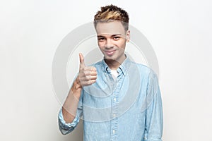 Smiling happy cheerful man showing like gesture, looking at camera, standing with thumb up.