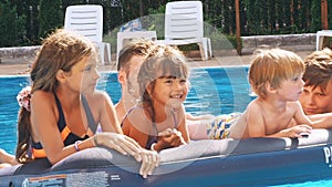 Smiling, happy children on a float in a swimming pool.