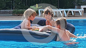 Smiling, happy children on a float in a swimming pool.