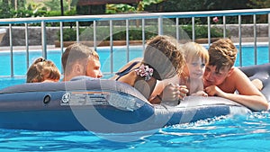 Smiling, happy children on a float in a swimming pool.