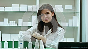 Smiling happy confident young woman pharmacist leaning on a desk in the pharmacy giving the camera a lovely big warm