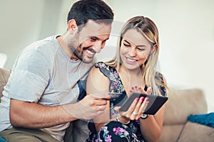 Smiling happy couple couple with tablet pc computer and credit card at home