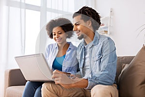 Smiling happy couple with laptop at home