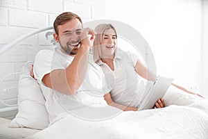 Smiling happy couple with a tablet computer in bed at home bedroom