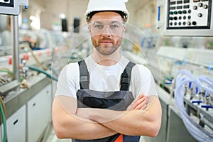 Smiling and happy employee. Industrial worker indoors in factory. Young technician with hard hat