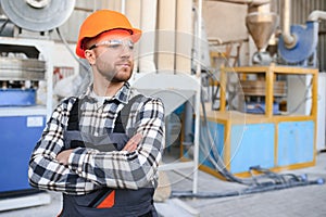 Smiling and happy employee. Industrial worker indoors in factory. Young technician with hard hat